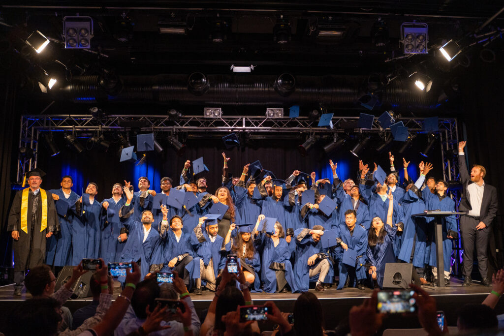 Global Production Engineering graduates throwing their caps in the air on stage at TU Berlin's traditional convocation celebration