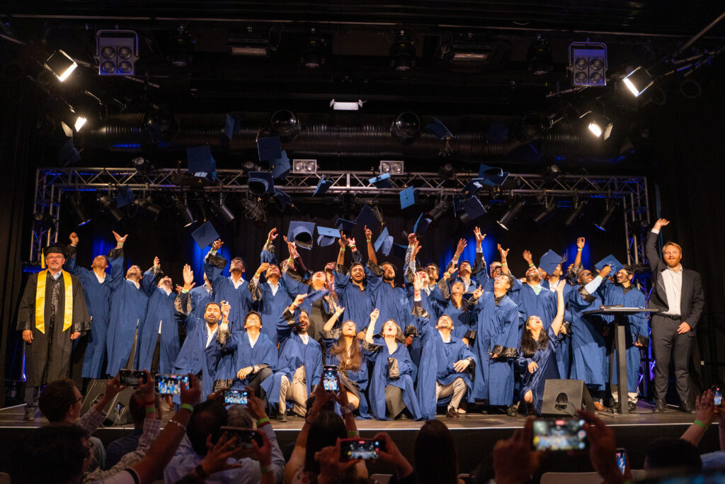 Wide shot of TU Berlin graduates tossing their caps during the closing moment of the 2026 convocation ceremony