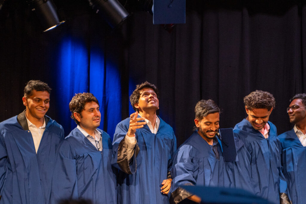 Graduates in academic gowns laughing and celebrating together, candid moment captured by a Berlin event photographer
